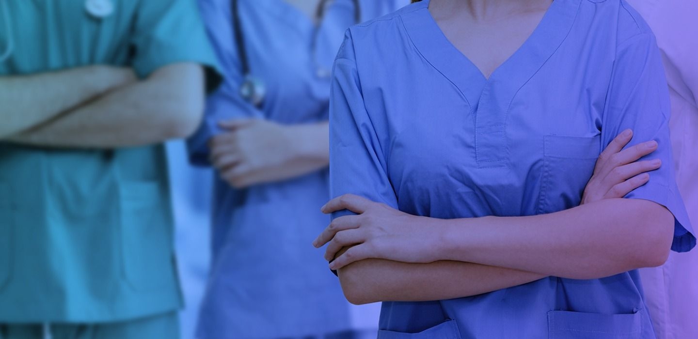 Three medical professionals with crossed hands standing, ready to help